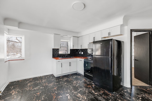 kitchen with butcher block countertops, white cabinetry, a sink, and black appliances