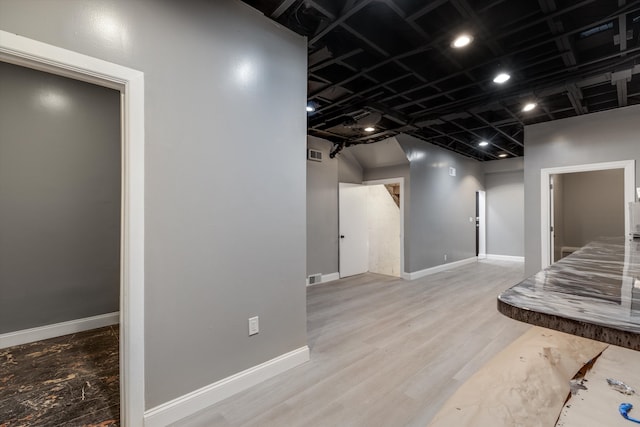 below grade area with wood finished floors, visible vents, and baseboards