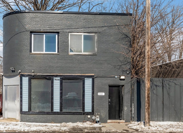 view of front facade with brick siding and fence