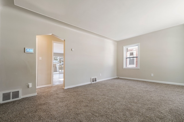 empty room featuring carpet floors, a healthy amount of sunlight, and visible vents