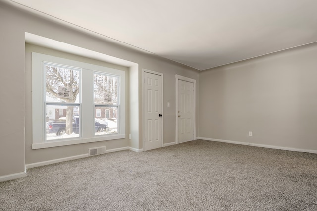 unfurnished room featuring carpet, visible vents, and baseboards