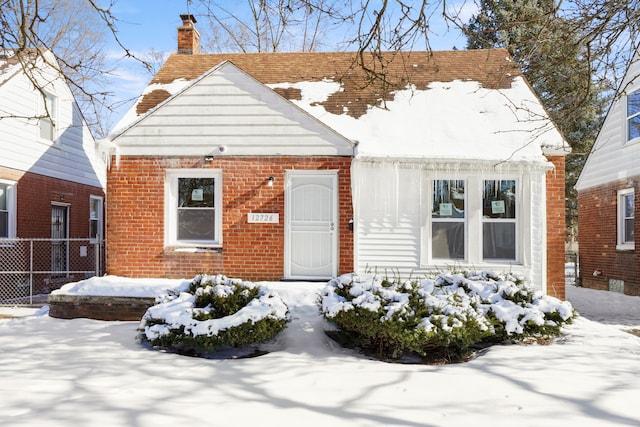 view of front of house with a chimney, fence, and brick siding