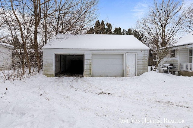 snow covered garage with a detached garage