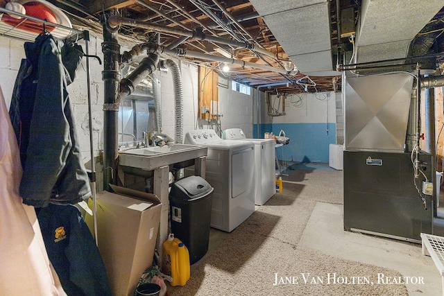 laundry room featuring laundry area, washer and clothes dryer, a sink, and heating unit