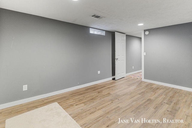 finished basement featuring light wood finished floors, visible vents, and baseboards