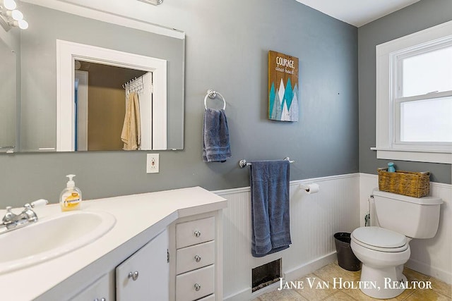 bathroom with tile patterned flooring, a wainscoted wall, vanity, and toilet