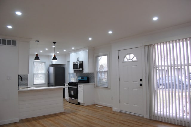 kitchen with stainless steel appliances, light countertops, visible vents, white cabinets, and a sink