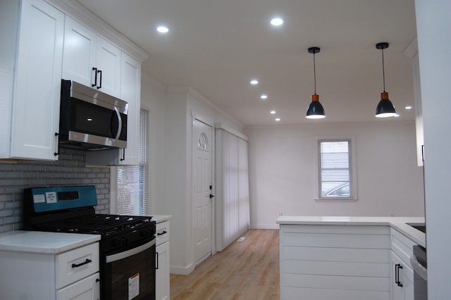 kitchen featuring hanging light fixtures, stainless steel microwave, black range with gas stovetop, and white cabinets