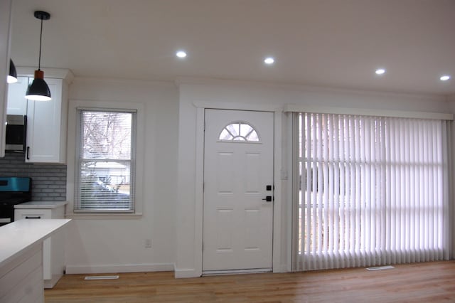 foyer with ornamental molding, light wood-type flooring, recessed lighting, and baseboards