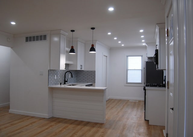 kitchen with tasteful backsplash, visible vents, white cabinetry, a sink, and a peninsula