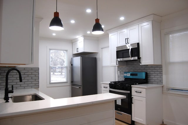 kitchen with light countertops, appliances with stainless steel finishes, a sink, and white cabinetry