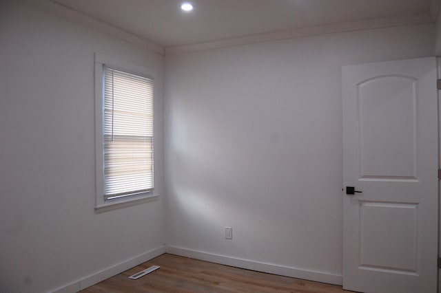 empty room featuring ornamental molding, wood finished floors, visible vents, and baseboards