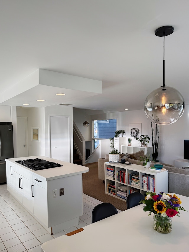 kitchen featuring pendant lighting, black gas cooktop, light countertops, freestanding refrigerator, and white cabinets