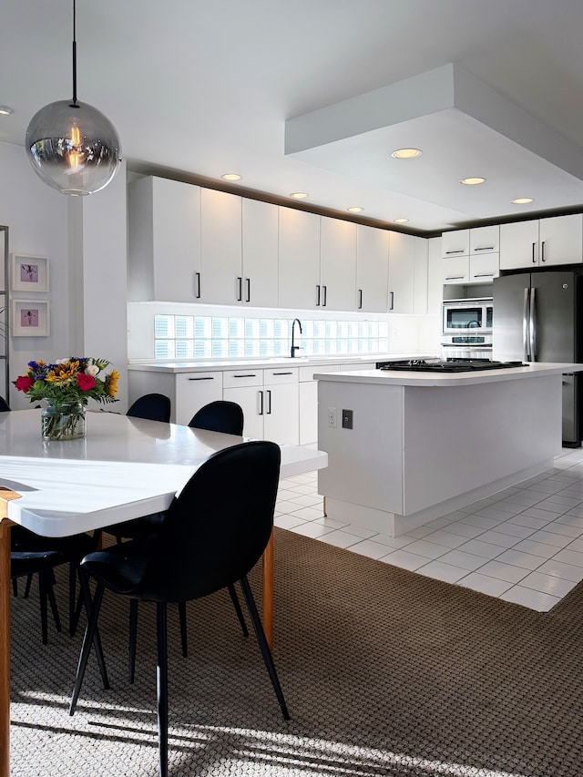 kitchen featuring appliances with stainless steel finishes, light countertops, white cabinets, and hanging light fixtures