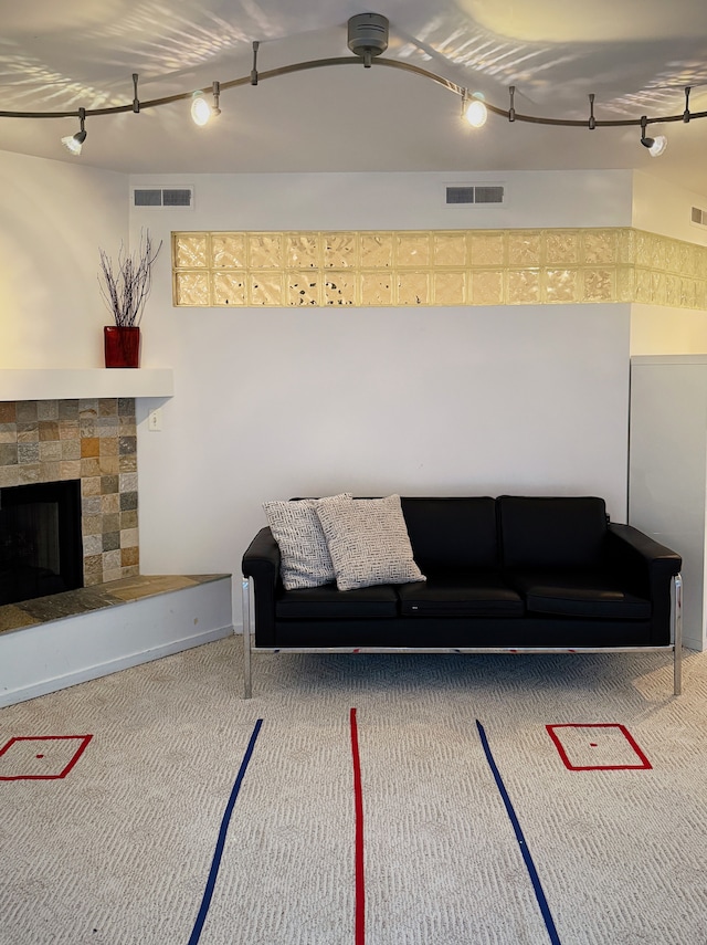 unfurnished living room with a stone fireplace, carpet flooring, and visible vents