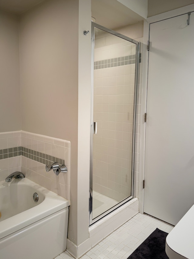 bathroom featuring a bath, a shower stall, and tile patterned flooring