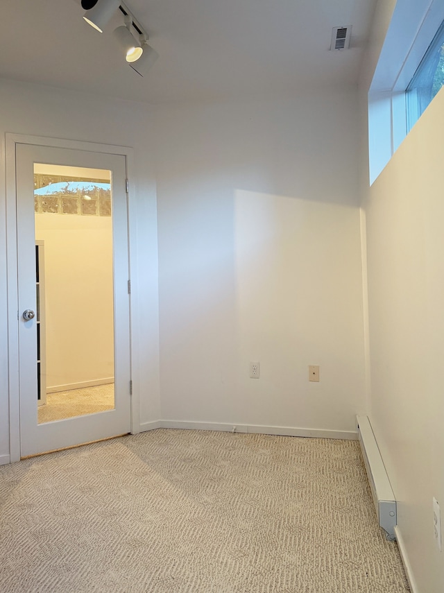 empty room featuring a healthy amount of sunlight, light carpet, visible vents, and baseboards