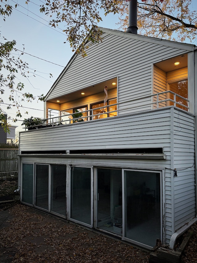 rear view of property featuring a balcony and fence