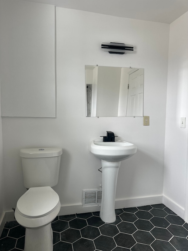 half bath featuring toilet, baseboards, visible vents, and tile patterned floors