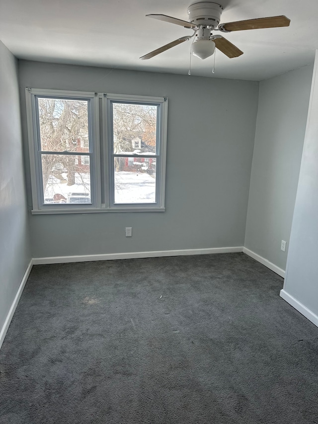 spare room featuring a ceiling fan, dark colored carpet, and baseboards