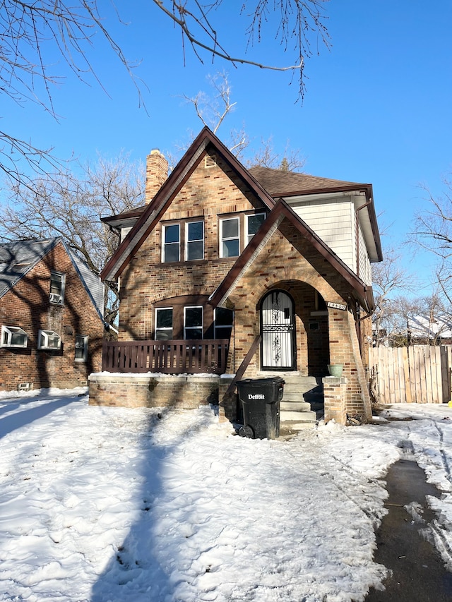 view of front of home with a chimney, fence, and brick siding