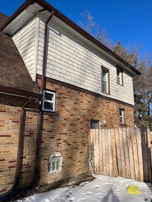 view of side of home featuring brick siding and fence