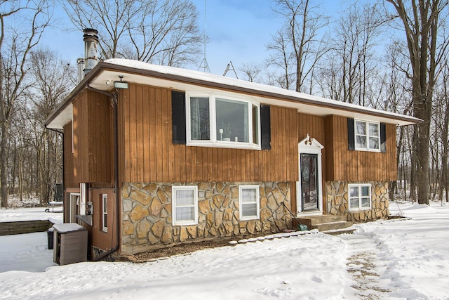 raised ranch featuring stone siding