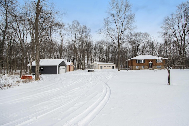 snowy yard featuring an outbuilding and a garage