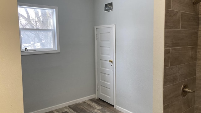 bathroom featuring plenty of natural light, baseboards, a tile shower, and wood finished floors