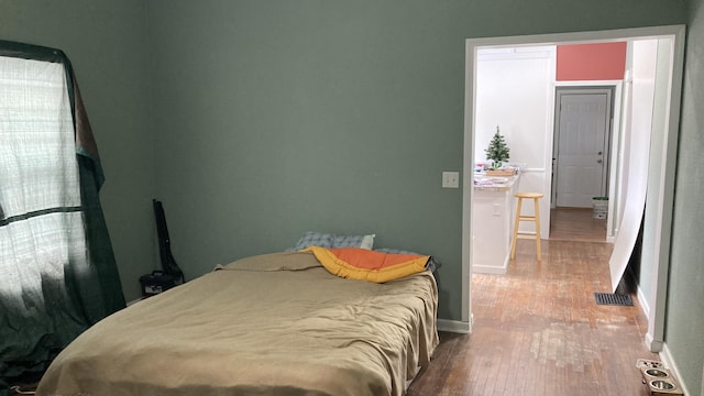 bedroom featuring baseboards, visible vents, and wood finished floors