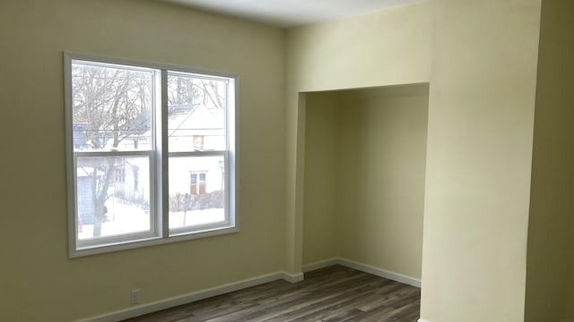 unfurnished room with baseboards and dark wood-type flooring