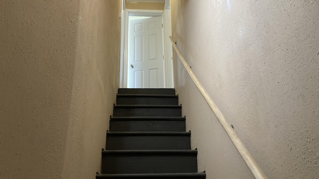 staircase featuring a textured wall