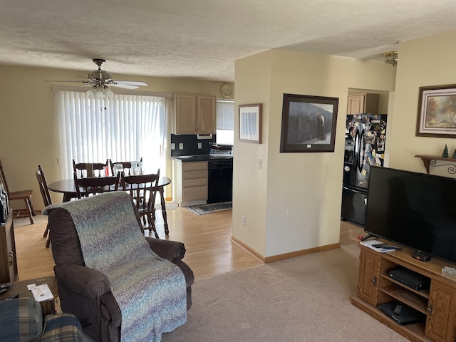 living area with baseboards, light colored carpet, a textured ceiling, and ceiling fan