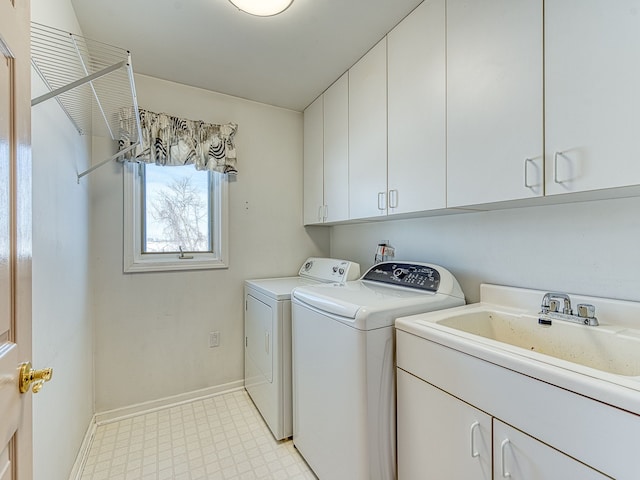 laundry area with cabinet space, baseboards, washer and clothes dryer, light floors, and a sink