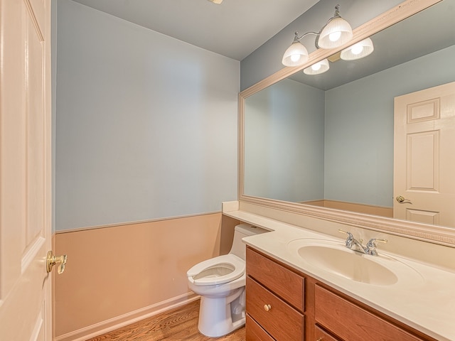 bathroom with toilet, wood finished floors, and vanity