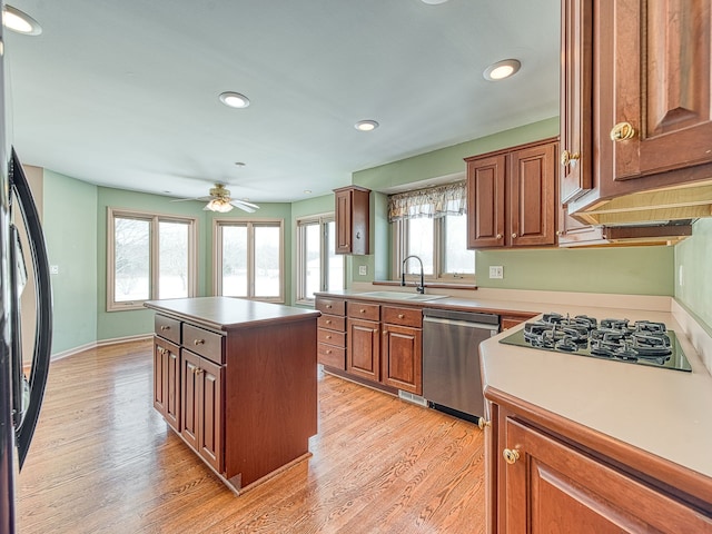 kitchen with a center island, brown cabinets, a sink, dishwasher, and fridge