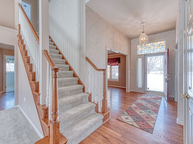 entryway with wallpapered walls, a high ceiling, wood finished floors, and baseboards