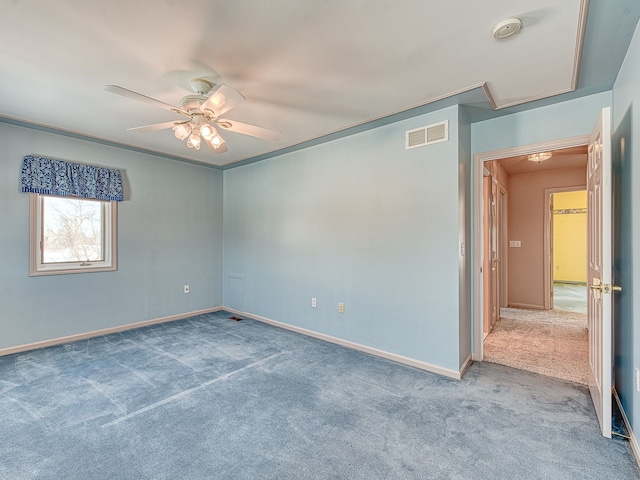 unfurnished room featuring carpet floors, visible vents, baseboards, and a ceiling fan