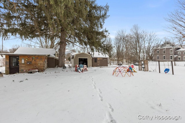 yard covered in snow featuring a garage and an outbuilding