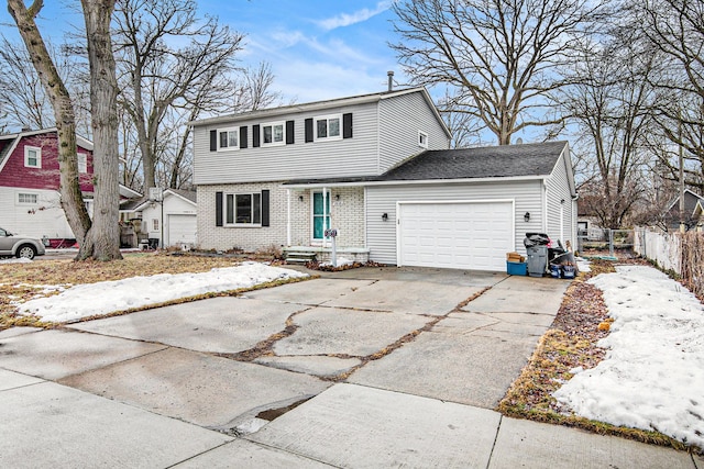 colonial home with a garage, brick siding, driveway, and fence