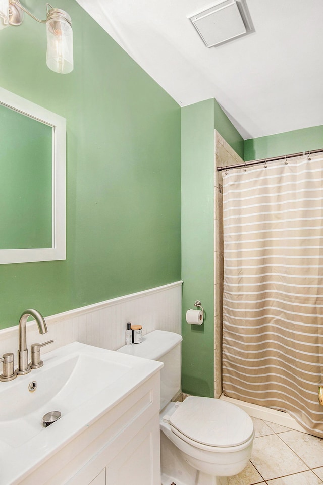 bathroom featuring curtained shower, tile patterned flooring, toilet, vanity, and wainscoting