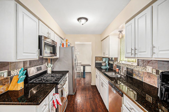 kitchen with stainless steel appliances, dark wood-style flooring, a sink, white cabinetry, and tasteful backsplash