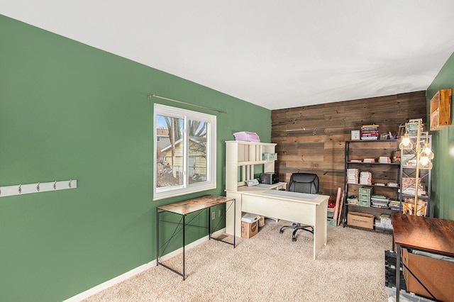 carpeted home office featuring wooden walls, an accent wall, and baseboards