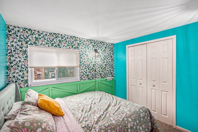 carpeted bedroom featuring a closet, wainscoting, and wallpapered walls