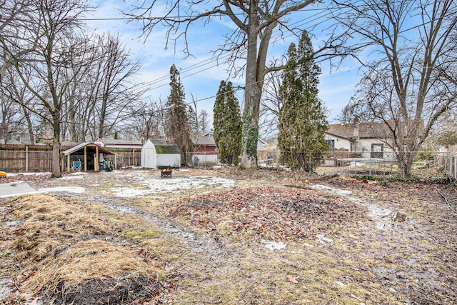 view of yard with a fenced backyard, a storage unit, and an outbuilding