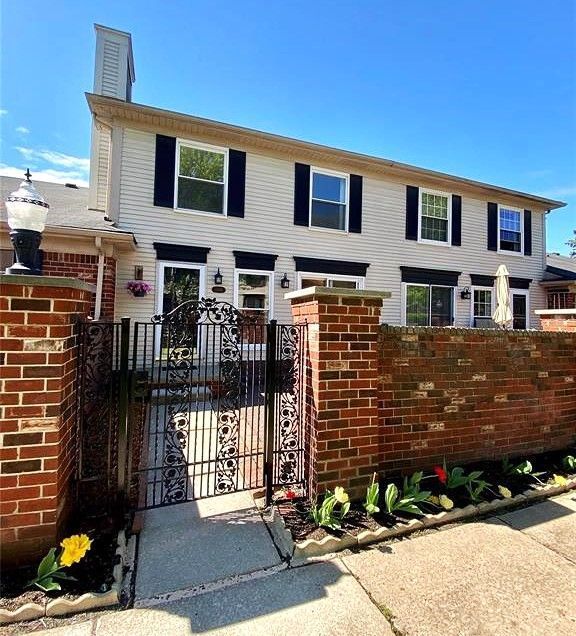 view of property featuring a chimney, a gate, fence, and brick siding