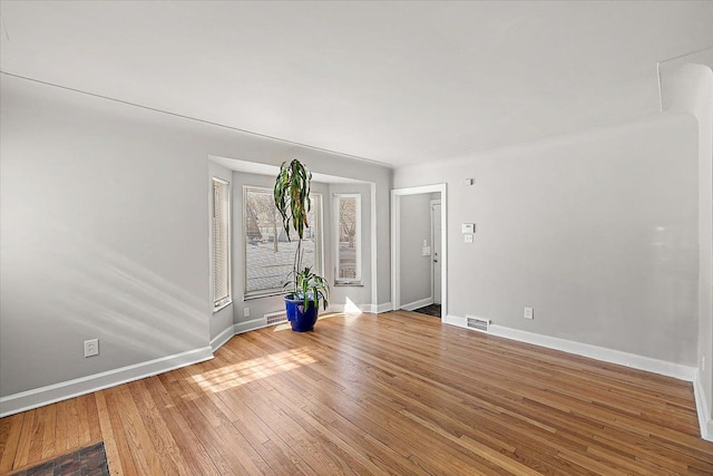 empty room featuring visible vents, baseboards, and wood finished floors