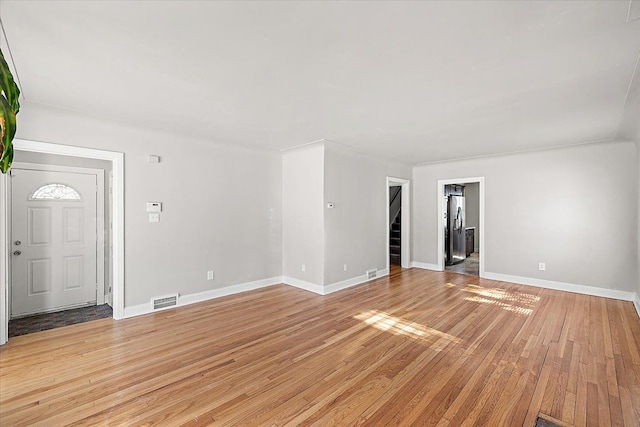 unfurnished living room featuring light wood-style flooring, stairs, visible vents, and baseboards