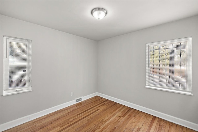 empty room featuring visible vents, baseboards, and wood finished floors