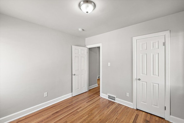 unfurnished bedroom with visible vents, light wood-style flooring, and baseboards